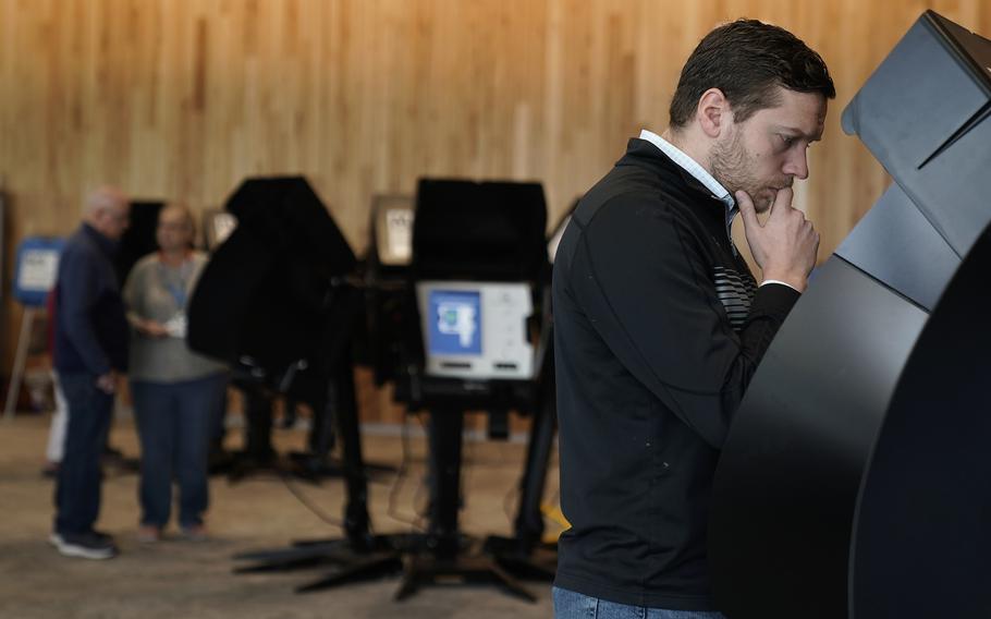 Tony Bergida looks over an electronic ballot while voting early at a polling place, Oct. 27, 2022, in Olathe, Kan. Bergida, a 27-year-old father of two and the chair of the Kansas Young Republicans, said the top issue on his mind as he cast his ballot was the economy. 