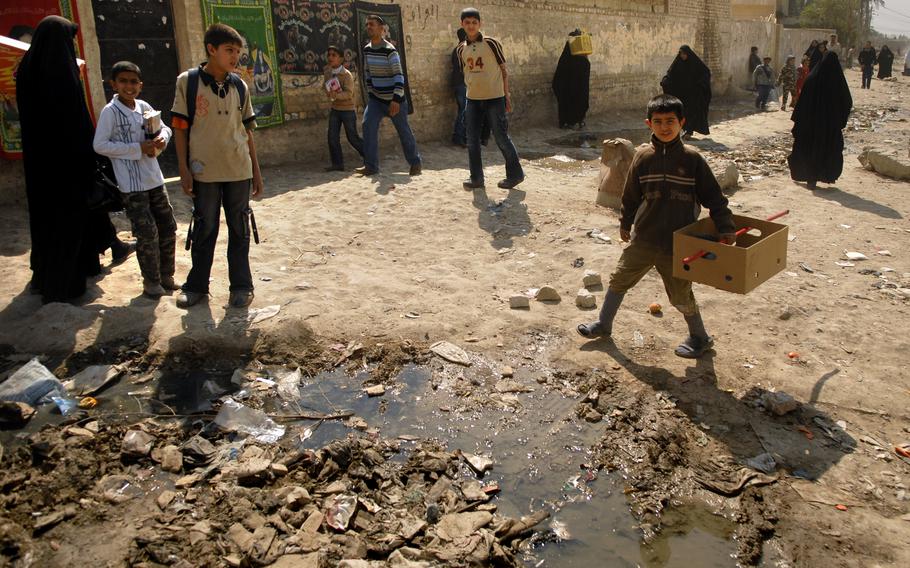 Residents seem unfazed by the surrounding filth just outside the market in Oubaidy, a suburb of Baghdad. 