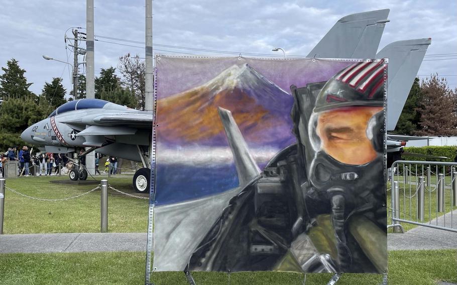 A painting on canvas of an aviator in the cockpit of an aircraft stands in front of a fighter jet.