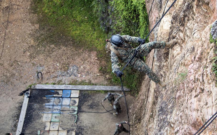 An above shot shows a Marine descending a cliff. 