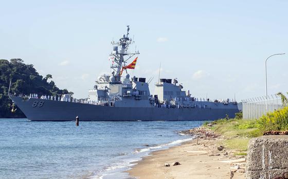 USS Preble is shown with a sandy shore and blue water in the foreground.