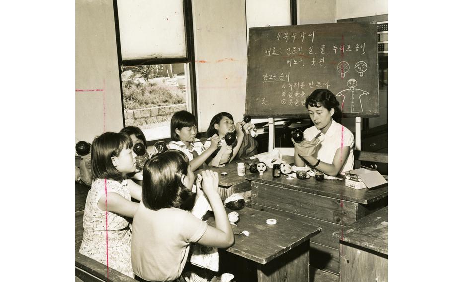 Children paint puppets in a classroom