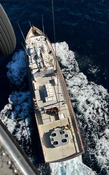 U.S. Air Force HH-60G Pave Hawk rescue helicopter hovers over a fishing vessel.