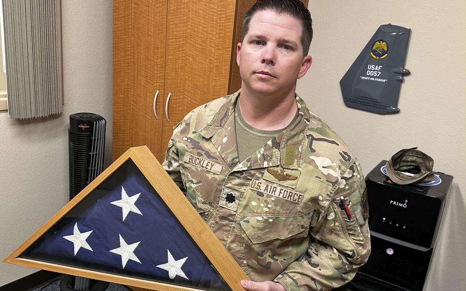 Lt. Col. Seth Buckley holds a folded flag in a shadow box as he poses for a portrait.