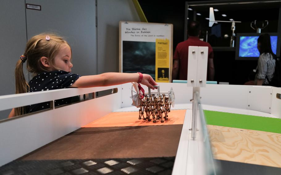 A girl plays with a small Strandbeesten, wind-driven constructs that mimic animal movements, at the Experimenta Science Center, in Heilbronn, Germany.