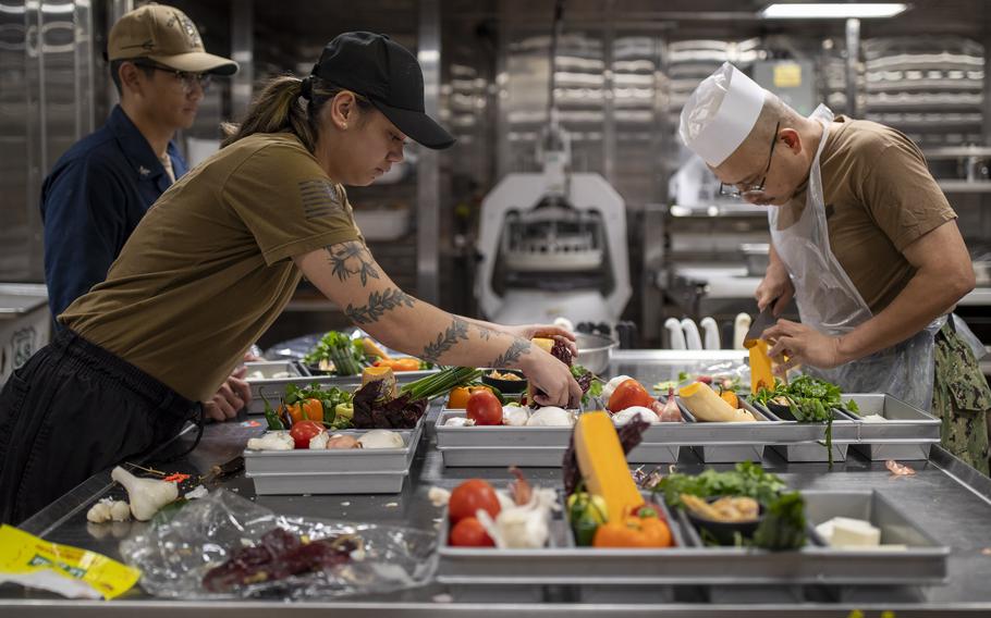 Culinary Specialists assigned to amphibious assault carrier USS Tripoli (LHA 7) prepare vegetables