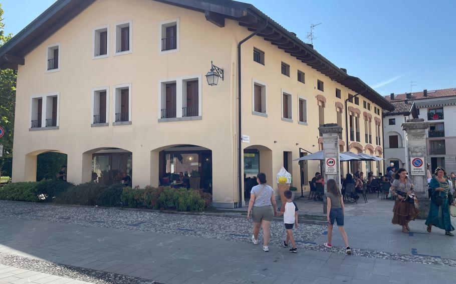 A family walks toward the entrance of Le Strane Delizie in Spilimbergo, Italy, on Aug. 17, 2024. The cafe is on the Piazza Borgolucido.