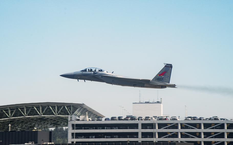 A plane takes off in front of a parking garage.