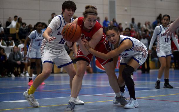 Kaiserslautern's Elizabeth Marriott fends off a challenge from Ramstein's Sanai Schneider, left, while fellow Royal Grayen Canady defends from behind during a Dec. 10, 2024, game at Ramstein High School on Ramstein Air Base, Germany.