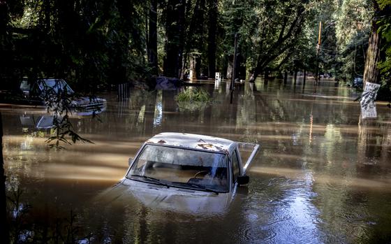 A car is halfway submerged in flooded water in Forestville, Calif.