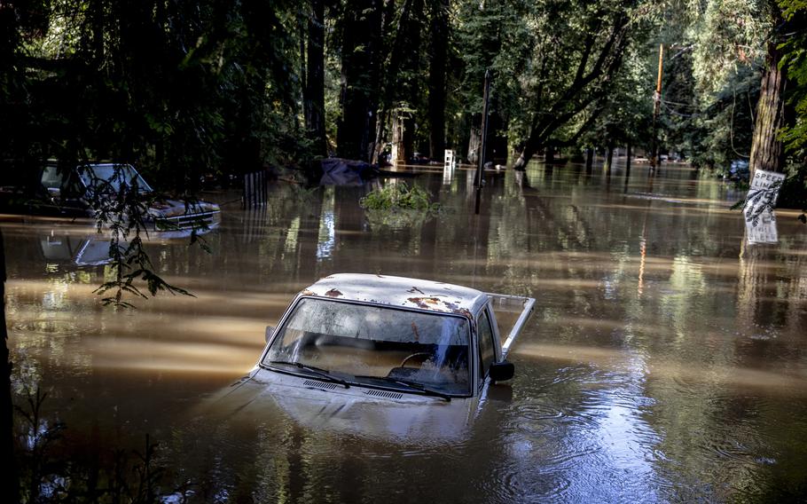 A car is halfway submerged in flooded water in Forestville, Calif.