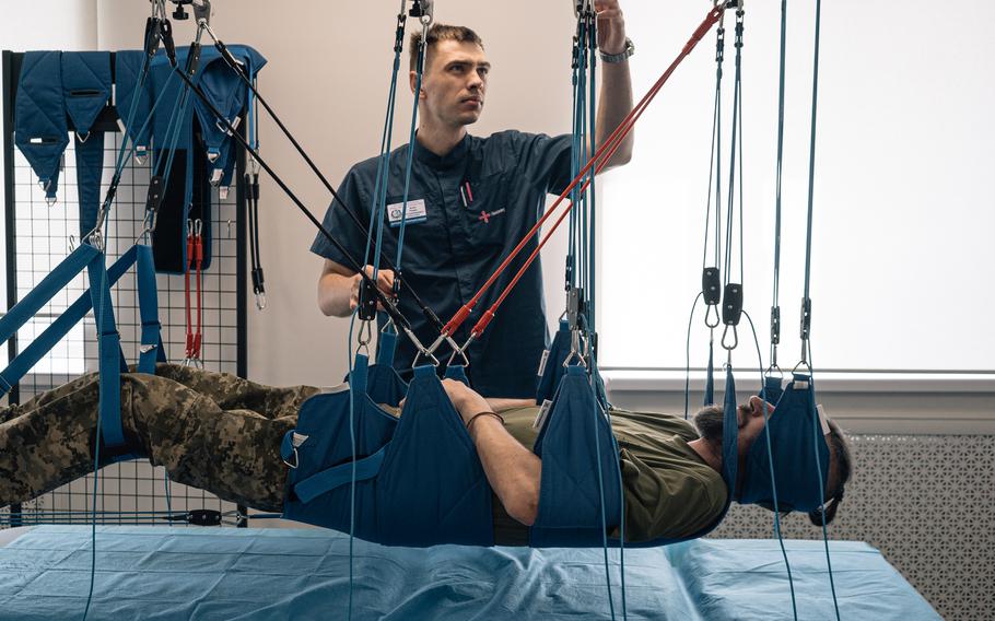 A Ukrainian service member, harnessed above a bed, undergoes physiotherapy Tuesday at a rehabilitation center in Dnipro, Ukraine.