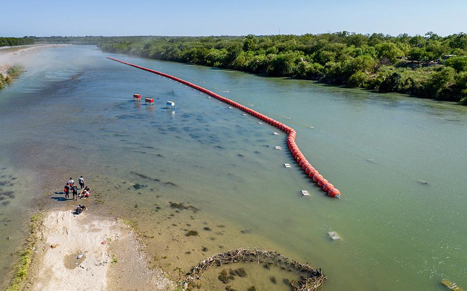 Migrants seeking asylum rest on an island while attempting to cross the Rio Grande river into the United States on July 18, 2023, in Eagle Pass, Texas. 