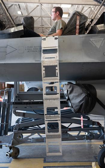 The side of an F-16 Viper is shown with the experimental ladder draped over the side, starting from the cockpit, where a person rests in the pilot’s seat.