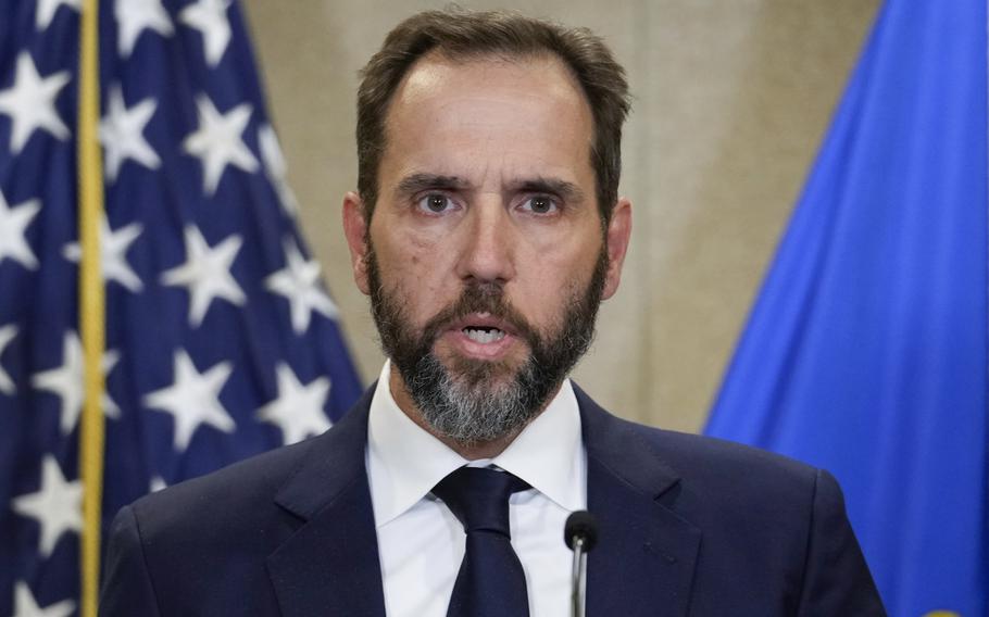 Special counsel Jack Smith speaks into a microphone while standing in front of a U.S. flag.