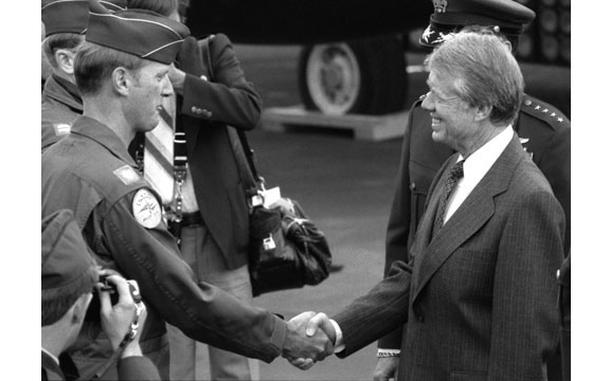 RHEIN-MAIN AB, Germany, July 16, 1978 — President Carter made a quick stop at the air base here where he left Air Force One and joined a motorcade heading to Wiesbaden Air Base. President Carter shakes hands with Maj. David H. Love, F-111 instructor pilot and aircraft commander, at Rhein-Main Air Base. Love said earlier that he was "very proud" to get his plane "polished up" as part of a static display of aircraft for the president.