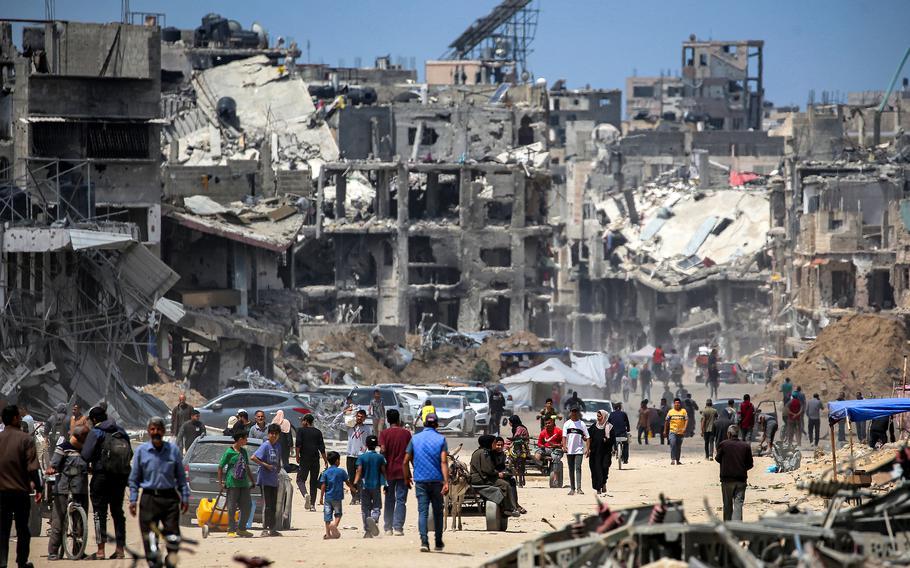 People move past destroyed buildings along a street in Khan Yunis in the southern Gaza Strip on May 14, 2024, amid the ongoing conflict in the Palestinian territory between Israel and Hamas.
