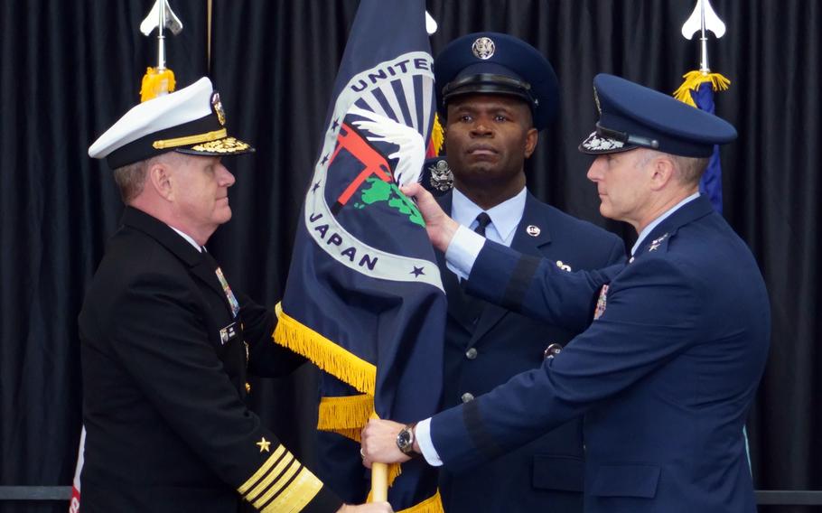 A U.S. Air Force general accepts the U.S. Forces Japan guidon from a U.S. admiral.