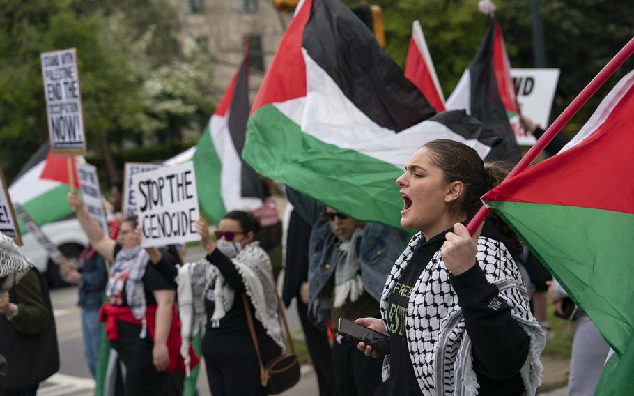 Protesters hold Palestinian flags and signs opposing the Israeli offensive in the Gaza Strip.