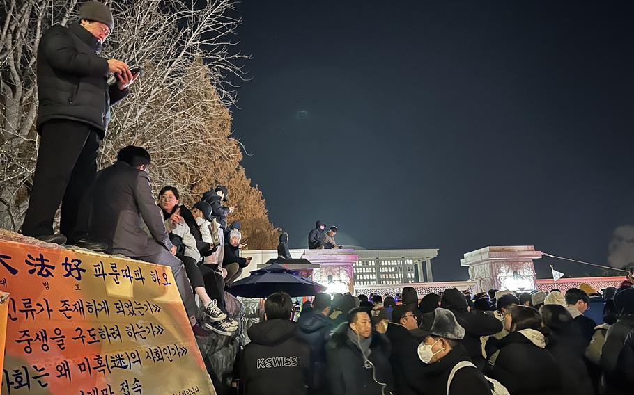 Protesters and observers are in a crowd near the National Assembly building in South Korea.