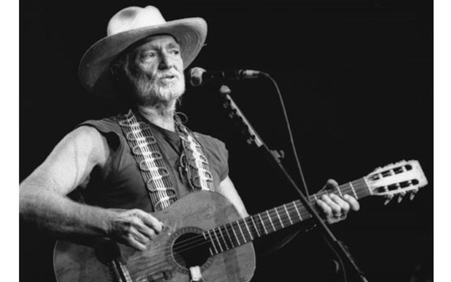 Willie Nelson performs on stage with a guitar