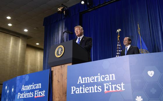 President Trump at a podium on a stage that has text reading “American Patients First.”