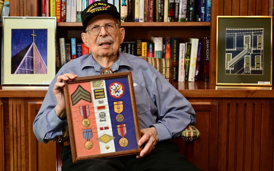 World War II veteran and retired Ramsey County (Minn.) Sheriff’s Deputy Herb Gustafson holds his service awards and insignias at Applewood Pointe in Woodbury, the senior cooperative where he lives, on Tuesday, Feb. 6, 2024. Displayed behind Gustafson is some of his art photography. 