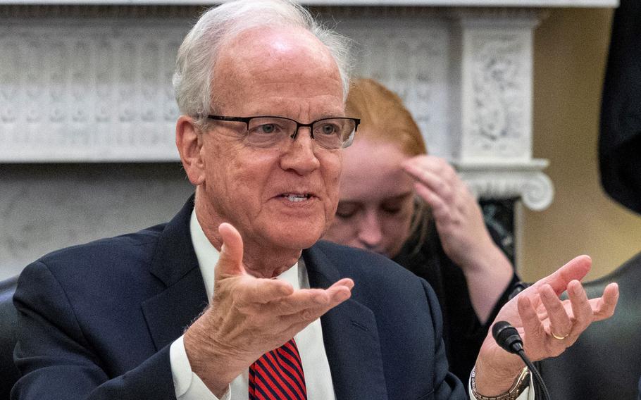 Moran is sitting and gesturing at a hearing.