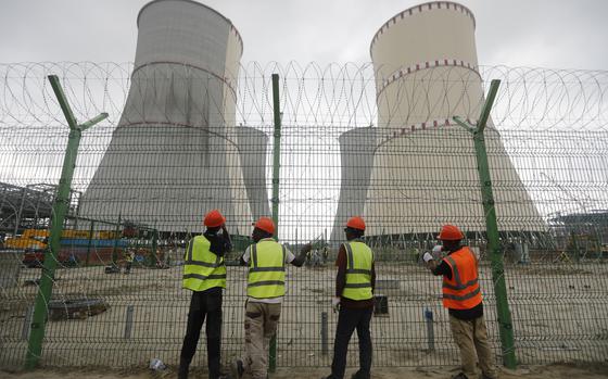 Workers fix barbed wire on the fence of the Rooppur Nuclear Power Plant ...