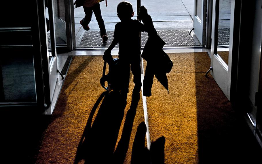 Students rush through the front door of their school after leaving the bus in Nelsonville, Ohio, on March 21, 2023. 