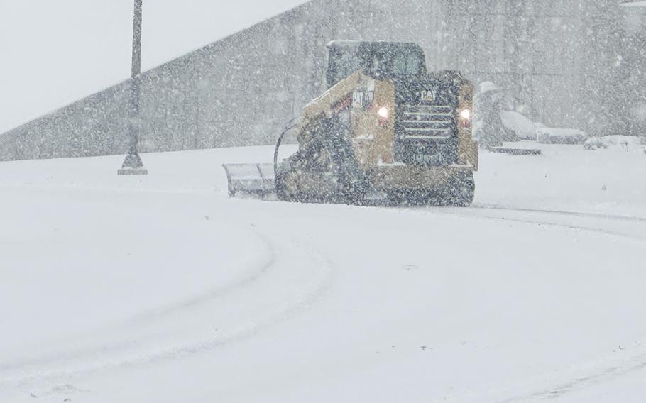 A worker in a CAT snow plow clears a street during a heavy snow storm.