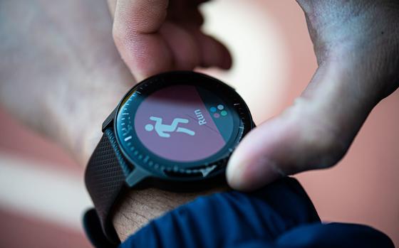 A close-up of a smartwatch on a wrist, with the other hand’s thumb and index finger adjusting it.