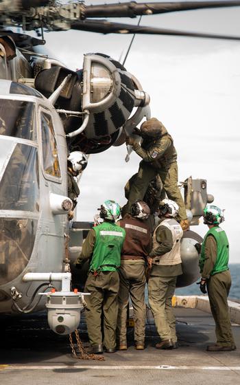 Marines examine an issue on a helicopter while onboard the USS New York.