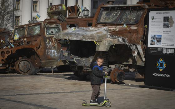 A boy rides a scooter past a display of destroyed Russian military vehicles in Mykhailivska square in central Kyiv, Ukraine, Tuesday, Oct. 22, 2024. (AP Photo/Efrem Lukatsky)