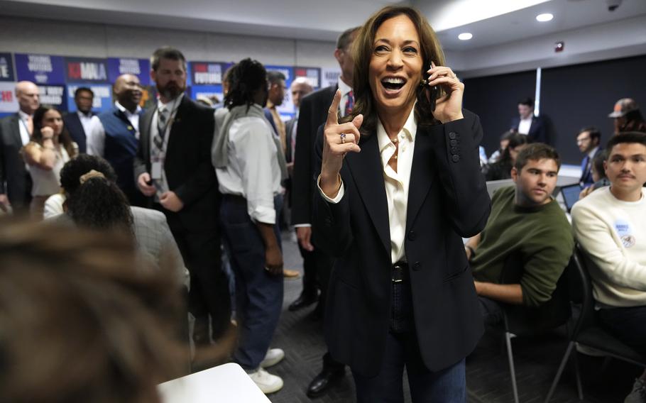 Vice President Kamala Harris in the center-right of the photo, holding a phone as she phone banks with volunteers in Washington, Nov. 5, 2024.