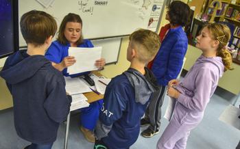 Sixth grade students stand in front of their teacher Susan Harris-Boring to recieve help on an assignment