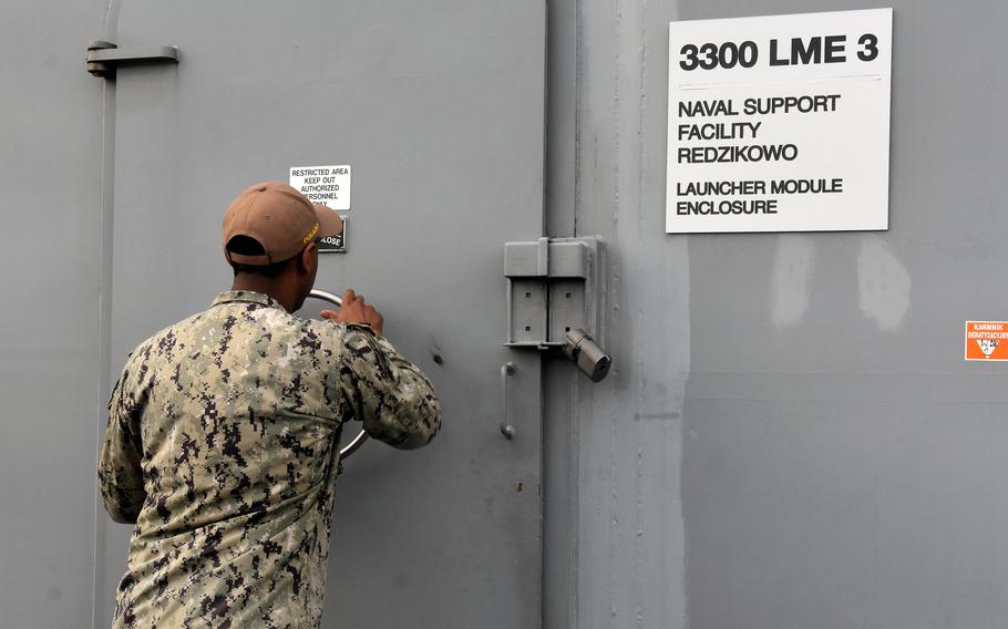 A sailor winds the lock as he closes the door of a missile launch site.