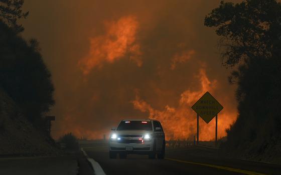 The Line Fire jumps highway 330 as an emergency vehicle is driven past Saturday, Sept. 7, 2024, near Running Springs, Calif. (AP Photo/Eric Thayer)