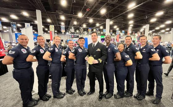 A tall man in a suit in the middle of a group of Air Force pilots posing for a photo.