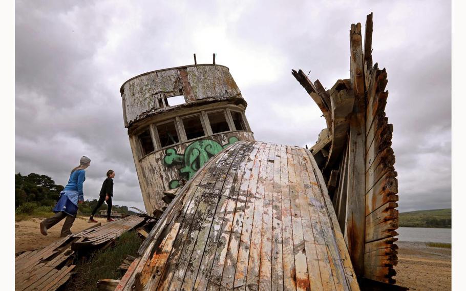 Visitors, on April 23, 2024, check out an old wooden boat that became an Instagram star as it rotted on a shoreline north of San Francisco. The boat was built in the 1940s and was used for transportation and fishing before it was abandoned years ago, aground near the community of Inverness on a section of the Tomales Bay shoreline that is part of the Point Reyes National Seashore. 