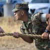 A Marine wearing a blouse with sleeves up tugs on a rope.