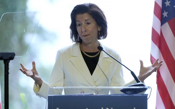 The U.S. secretary of commerce gestures with her hands while standing at a podium and speaking into a microphone.