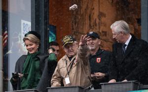 World War II veteran Dennis Bolt throws nuts to a crowd as part of the annual Battle of the Bulge commemorations in Bastogne, Belgium, Dec. 14, 2024. He is joined by Belgium's Queen Mathilde, left, and King Philippe, far right. 