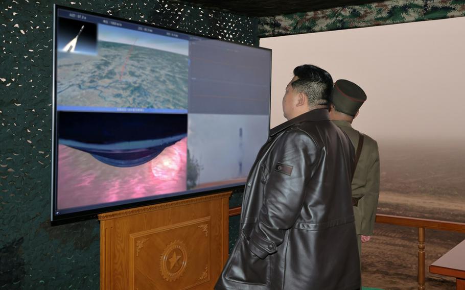 Kim Jong Un watches a screen showing an intercontinental ballistic missile being launched.