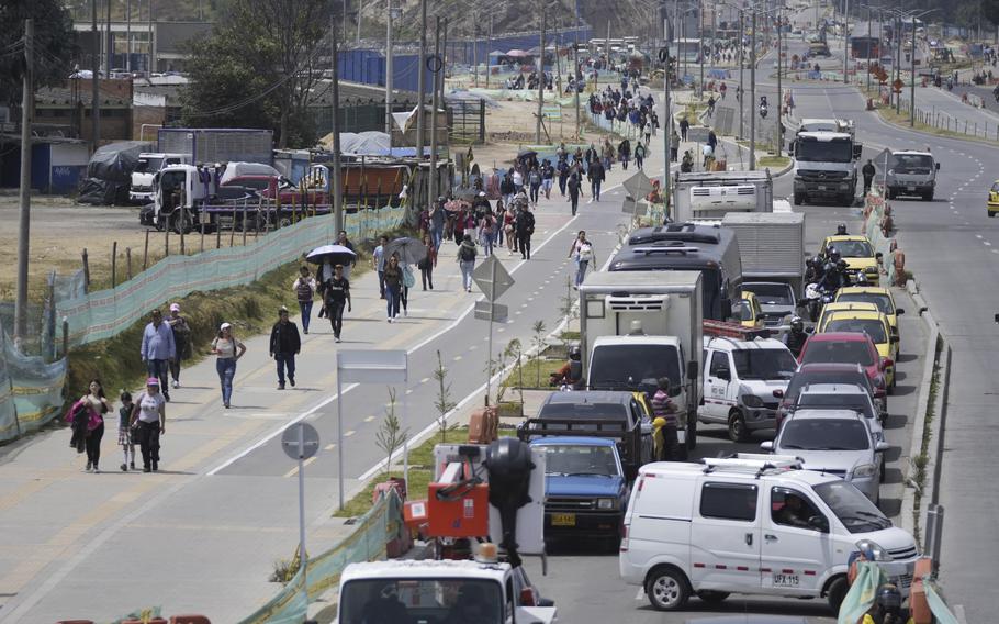 Commuters walk along an avenue blocked by truckers