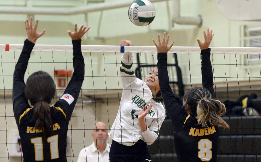 Kubasaki's Yuri Biggins spikes between Kadena's Leighton Botes and Lia Connolly during Tuesday's Okinawa volleyball match. The Dragons won in four sets.