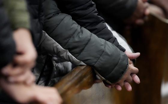 Hands clasped over a pew in a church.