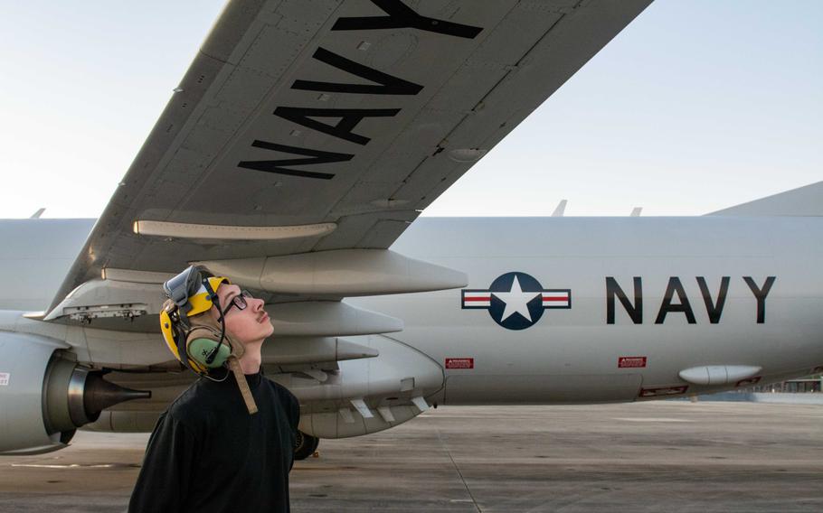 Sailor looking up at the wing of a plane to inspect it.