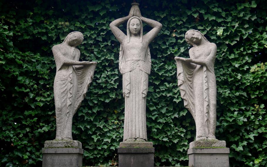 A fountain with three female figures in a grove.