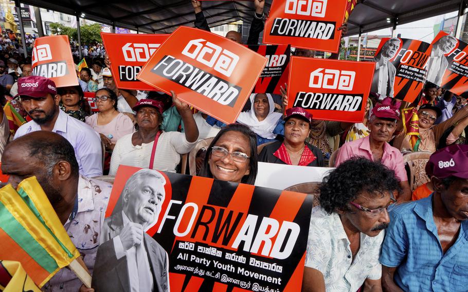 A woman supporter of Sri Lankan President and independent presidential candidate Ranil Wickremesinghe, holds a placard at an election rally in Minuwangoda, Sri Lanka.